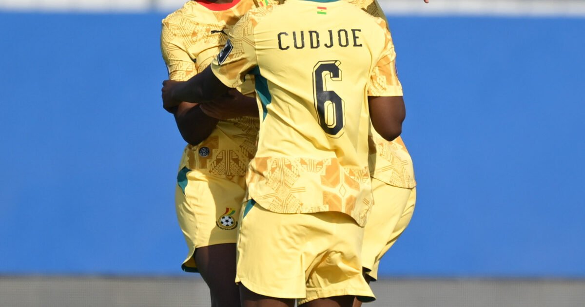 Soccer players in yellow uniforms embrace on the field showing the name CUDJOE and number 6 on one jersey