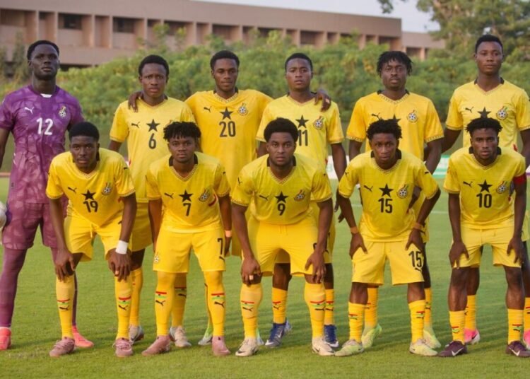 Football team photo eleven players in yellow uniforms posing on the field goalkeeper in purple on the left