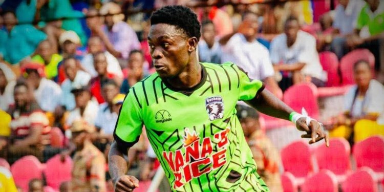 Soccer player in a neon green jersey sprinting on the field with a crowd watching from red seats in the stands