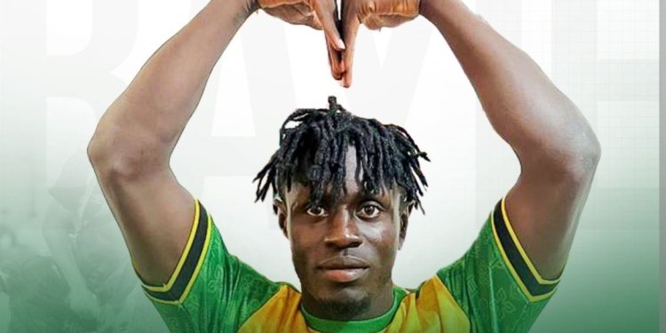 Soccer player in green and yellow jersey raises arms to form a heart shape