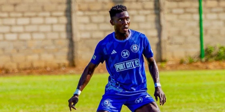 Soccer player in a blue Port City FC kit with the number 34 crouched and ready on a grassy field during a game