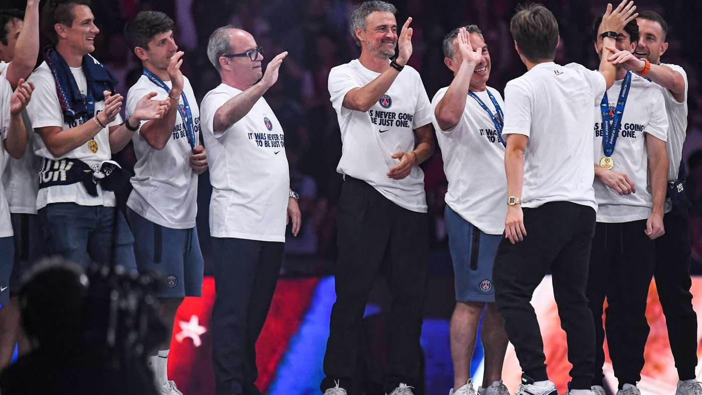 Group of players in white shirts with medals celebrating on stage giving high fives after a victory