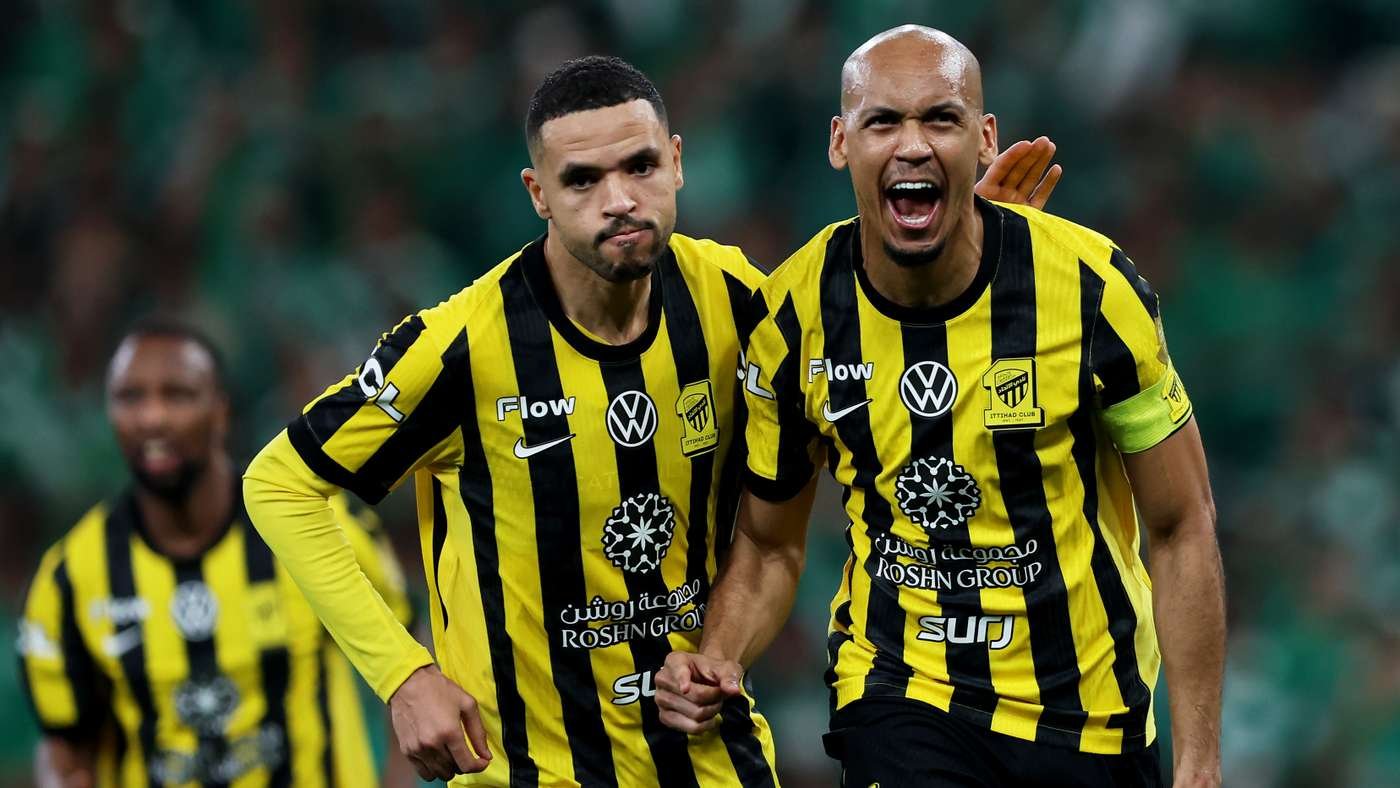 Two soccer players in yellow and black striped jerseys celebrate on the field