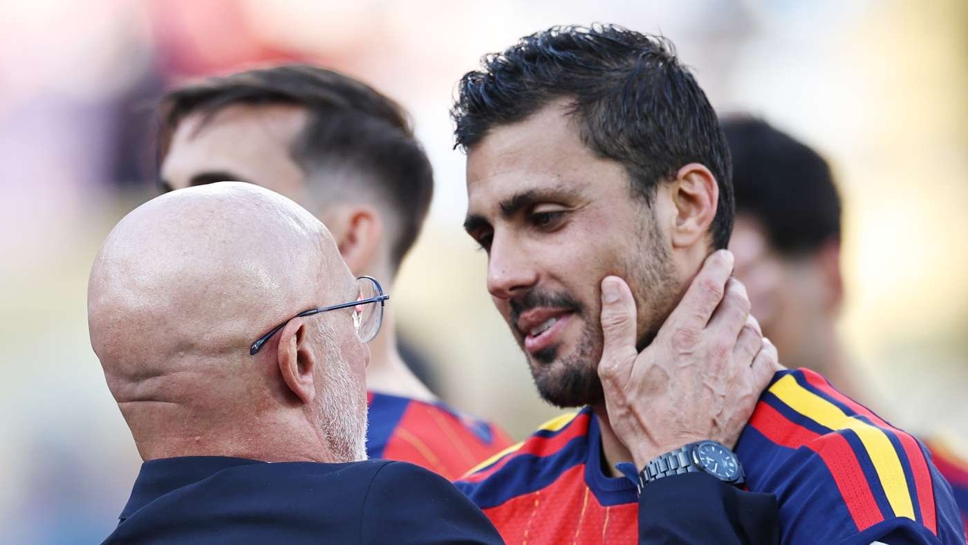 Coach cradling a players face in a supportive moment during a match player wears a red blue striped jersey
