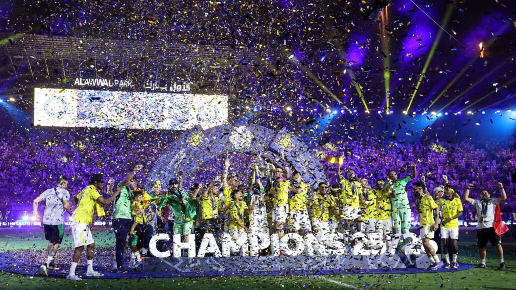 Soccer team in yellow jerseys celebrates on the field with confetti raining down and a large CHAMPIONS sign.