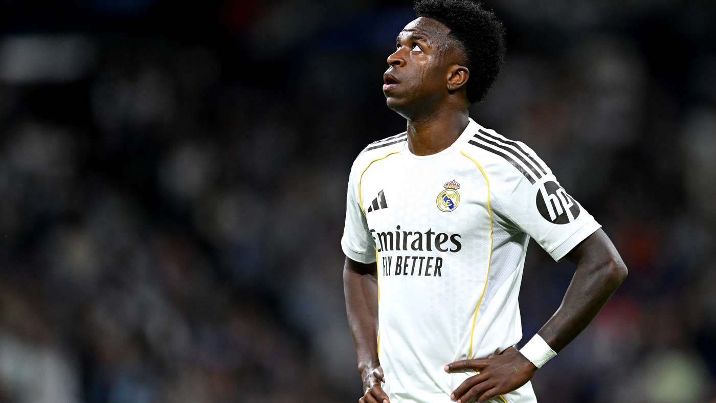 Footballer in a Real Madrid white kit stands with hands on hips gazing upward on the field
