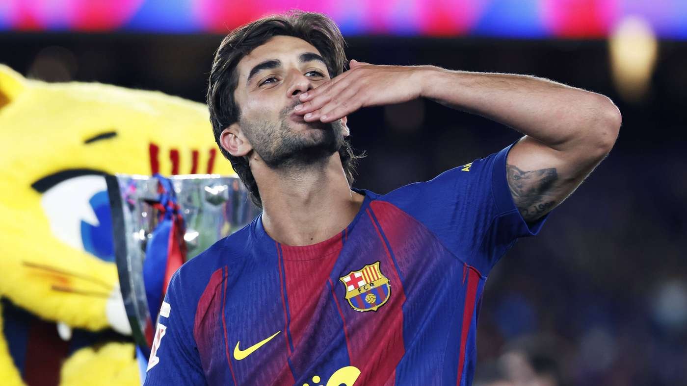 Barça player in blue red jersey blows a kiss in celebration trophy and mascot in the background